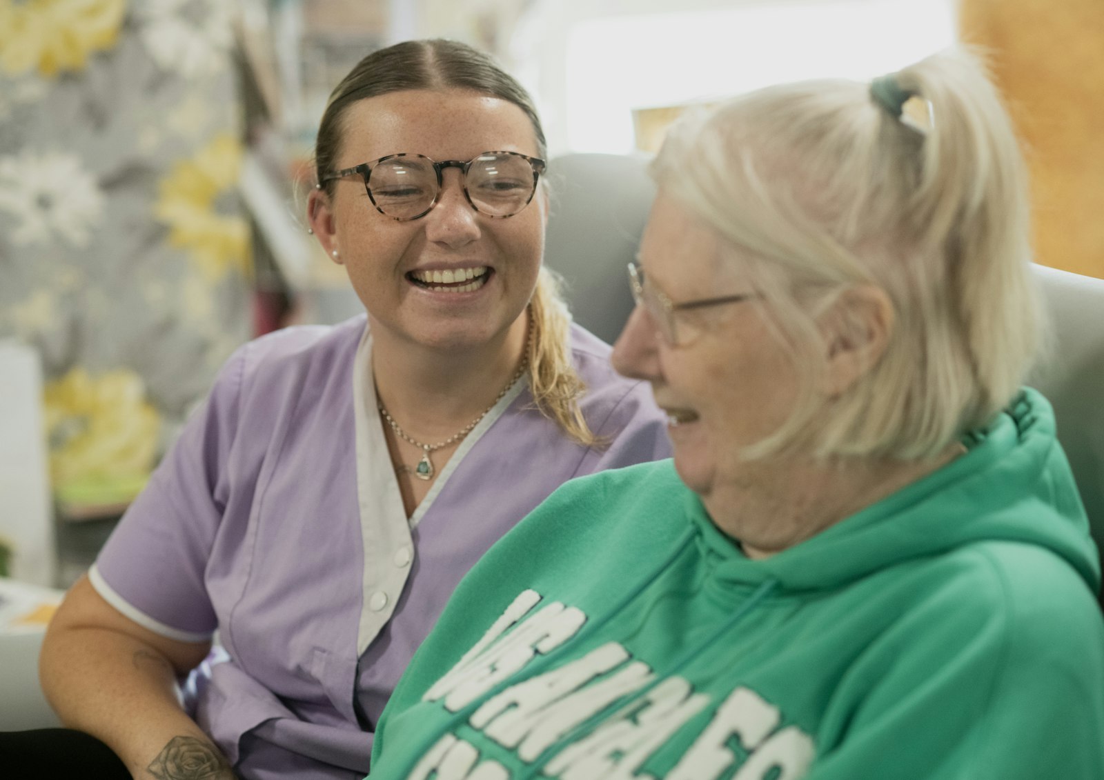 A caregiver laughing warmly with a senior client
